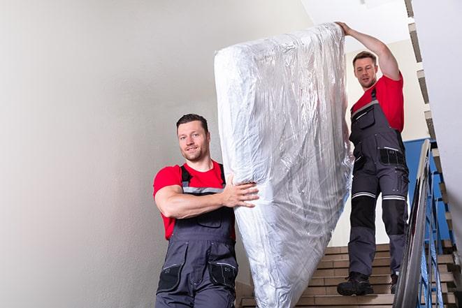 team carrying a large box spring out of a bedroom in Burlington